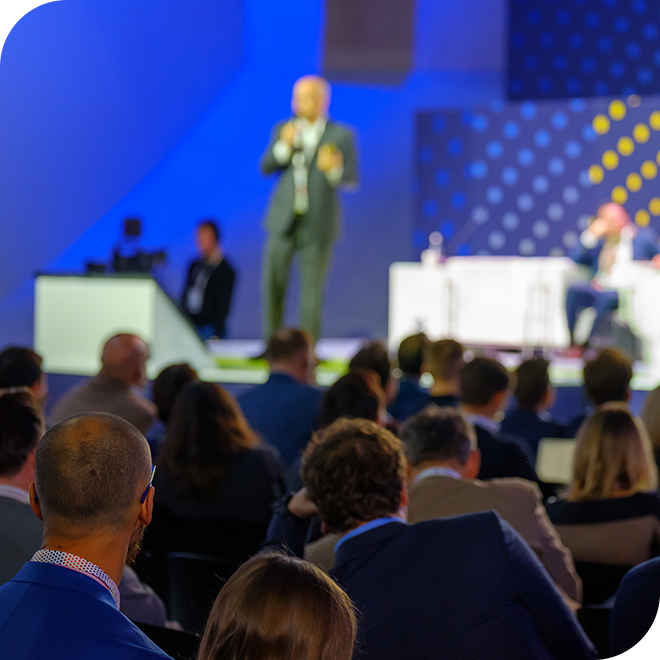 Man speaking on stage to a crowd at a conference
